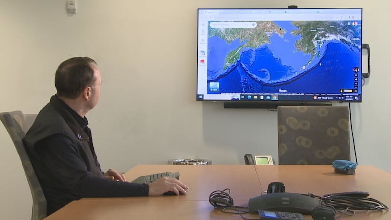 Historian, Michael Livingston, looks at a map of the Aleutian Islands.