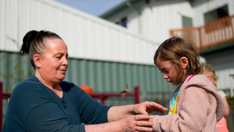 Associate educator Patty Kramer helps Moriah Wallen, 5, as they release a butterfly hatched in...