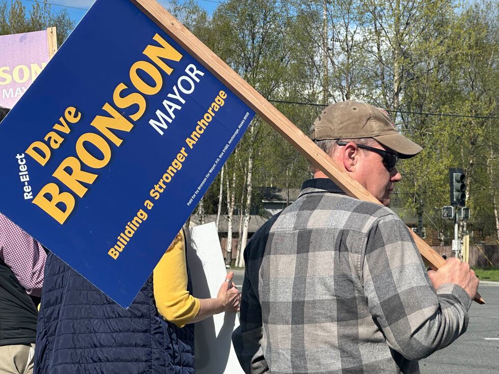 Anchorage Mayor Dave Bronson holds a campaign sign on the side of the road on Election Day.