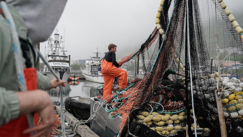 Deckhands stack nets on a boat before heading out to sea to fish salmon, Thursday, June 22,...