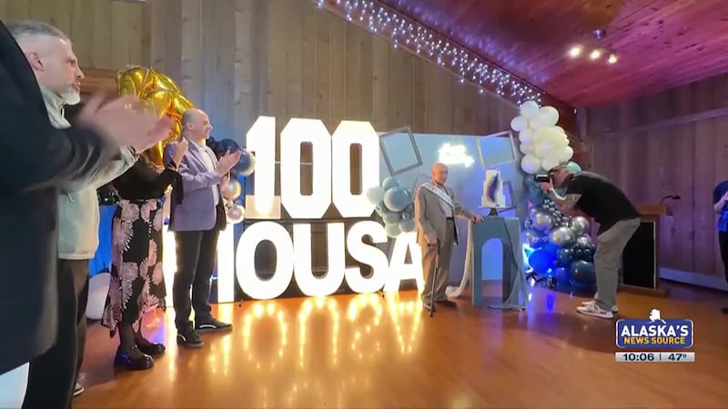 Mousa Obeidi stands beside his birthday cake at the celebration of his 100 years of life